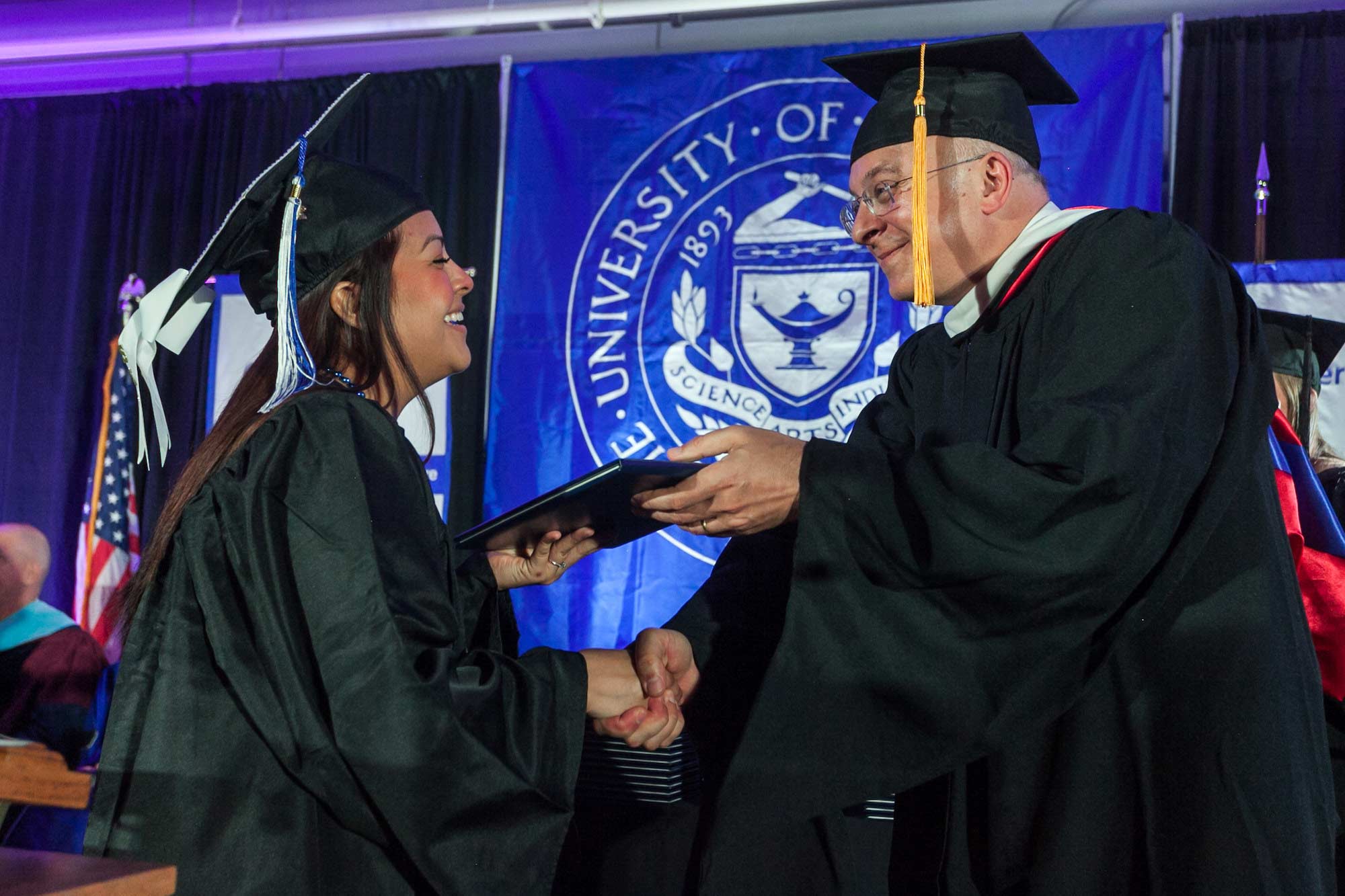 Dean giving student diploma at graduation