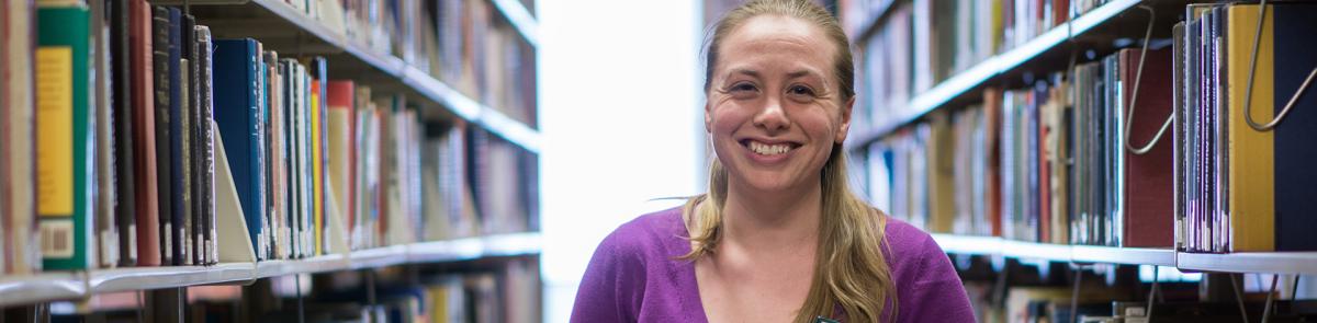 Student standing in library book stacks