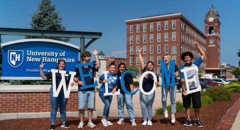 students holding welcome sign in front of UNH Manchester