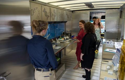 The inside of the STEM-MoBILE with people looking at science displays and smiling.