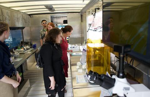 The inside of the STEM-MoBILE with people looking at science displays.