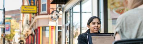 Two students in downtown Manchester with an open laptop