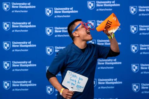 UNH Manchester student with a thank you sign, oversized clown glasses, and a megaphone