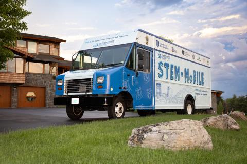 A large step-van with the words "STEM-MoBILE" on the side with a picturesque background.